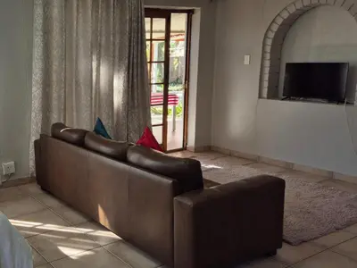 a brown couch in a living room with a television at 19th on Bloekom Guesthouse in Secunda