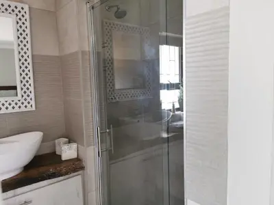 a bathroom with a glass shower and a sink at 19th on Bloekom Guesthouse in Secunda