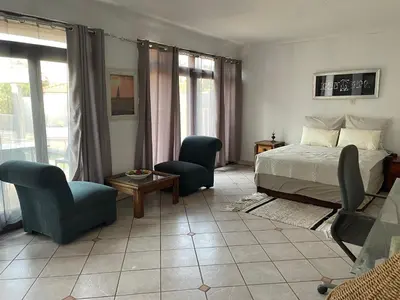 a bedroom with a bed and two chairs and a tv at Royal View Cottage in Hartbeespoort