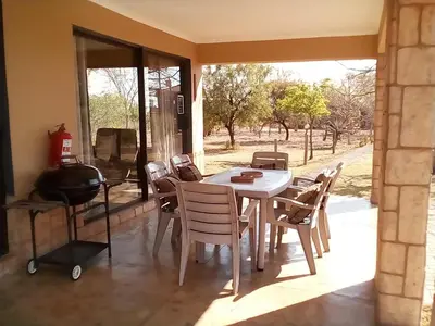 a dining room with a table and chairs and a grill at Nyani Lodge Dinokeng in Pretoria