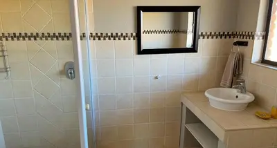 a bathroom with a sink and a shower with a mirror at Fish Eagle Villa in Hoedspruit