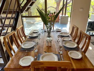 a wooden table with plates and wine glasses on it at Fish Eagle Villa in Hoedspruit