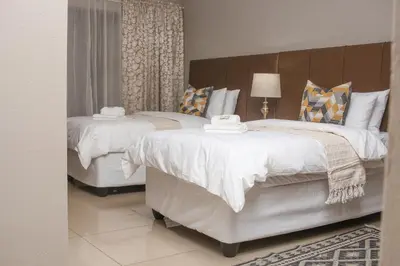 a bedroom with two beds with white comforters at Senaville Guesthouse in Louis Trichardt