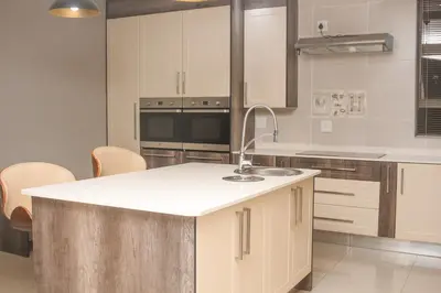 a kitchen with white cabinets and a white counter top at Senaville Guesthouse in Louis Trichardt