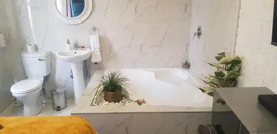 a white bathroom with a toilet and a tub and a sink at Ko-Porch luxury guest house in Polokwane