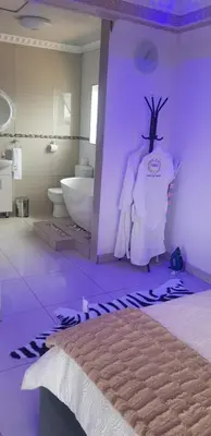a purple room with a bed and a bathroom at Ko-Porch luxury guest house in Polokwane