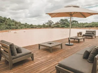 a wooden deck with chairs and an umbrella at Thaba eNtle Private Boutique Game Farm in Thabazimbi