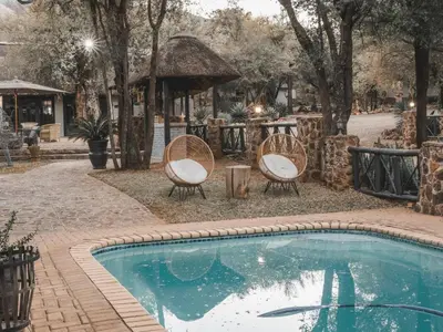 a swimming pool with two chairs and a gazebo at Thaba eNtle Private Boutique Game Farm in Thabazimbi