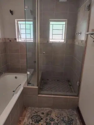 a bathroom with a tub and a shower with a glass door at 54 Brecher in Pretoria