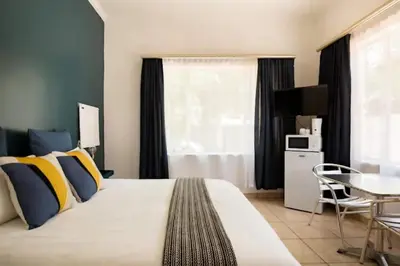 a bedroom with a large bed with yellow and blue pillows at 54 Brecher in Pretoria