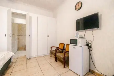 a room with a small refrigerator and a tv on the wall at 54 Brecher in Pretoria