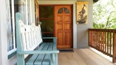a porch with a blue bench and a wooden door at 5th Seasons Guesthouse in Nelspruit