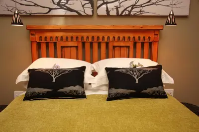 a bed with two black and white pillows on it at 5th Seasons Guesthouse in Nelspruit