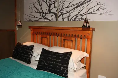 a bed with a wooden headboard and two pillows at 5th Seasons Guesthouse in Nelspruit