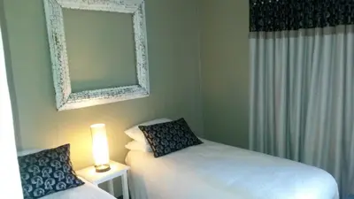 a bedroom with two beds and a mirror and a lamp at 5th Seasons Guesthouse in Nelspruit