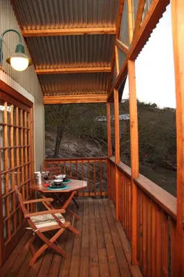 a wooden deck with a table and chairs on it at 5th Seasons Guesthouse in Nelspruit
