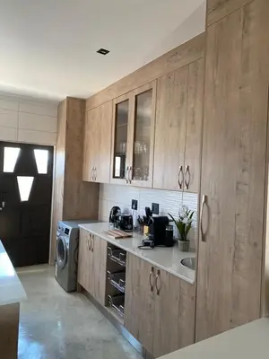 a kitchen with wooden cabinets and a sink and a washing machine at Maratongfontein Euphoria Villa in Naboomspruit