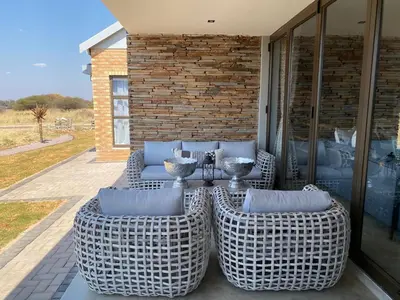 a group of wicker chairs and tables on a patio at Maratongfontein Euphoria Villa in Naboomspruit
