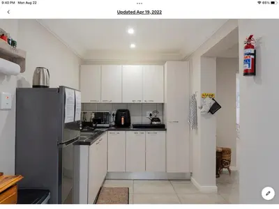 a kitchen with white cabinets and a black refrigerator at Rueby’s Apartment 101 in Dullstroom
