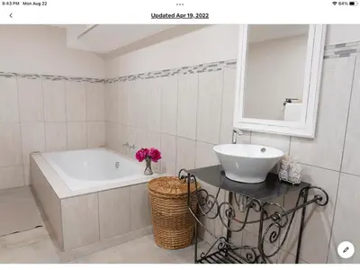 a bathroom with a tub and a sink and a mirror at Rueby’s Apartment 101 in Dullstroom