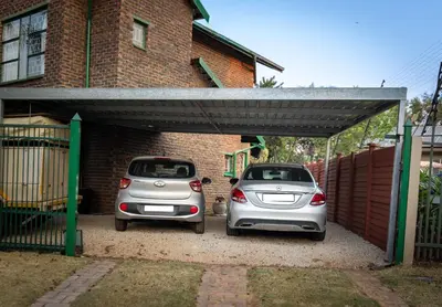 two cars parked under a garage in front of a house at VillaZek a modern 2 bedroom open- plan apartment with parking in Pretoria