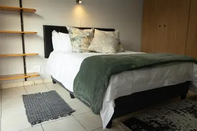 a bedroom with a bed with a green blanket and pillows at VillaZek a modern 2 bedroom open- plan apartment with parking in Pretoria