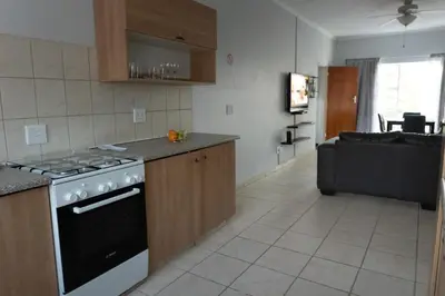 a kitchen with a stove and a living room at VillaZek a modern 2 bedroom open- plan apartment with parking in Pretoria