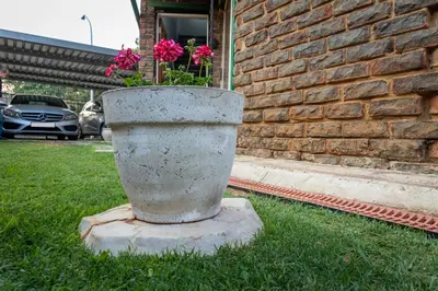 a concrete planter with flowers in it in the grass at VillaZek a modern 2 bedroom open- plan apartment with parking in Pretoria