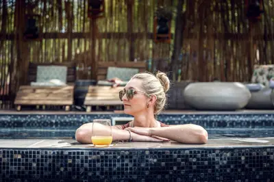 a woman laying in a swimming pool with a glass of orange juice at Grace of Africa Boutique Safari Lodge in Marloth Park