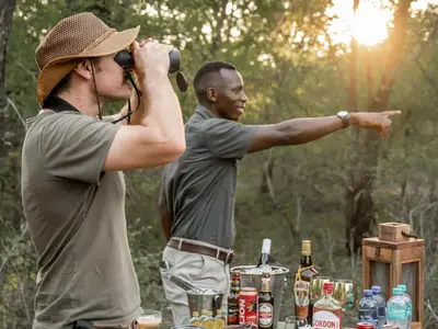 two men standing next to a table with bottles of beer at Grace of Africa Boutique Safari Lodge in Marloth Park