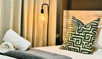 a bed with a black and white pillow and a lamp at Oost Street in Polokwane