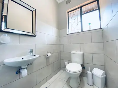 a bathroom with a toilet and a sink and a mirror at Oost Street in Polokwane