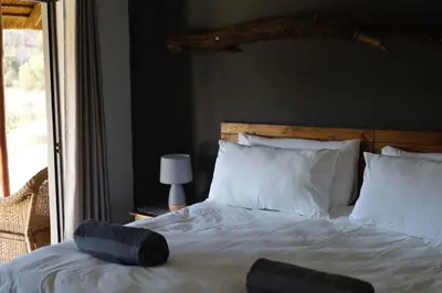 a bedroom with a white bed with a large window at Waterberg Game Lodge in Bela-Bela