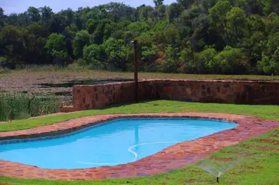 a brick retaining wall around a pool in a field at Waterberg Game Lodge in Bela-Bela