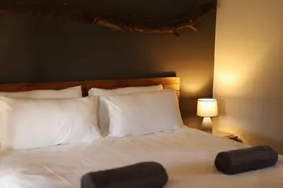 a bed with white pillows and a wooden headboard at Waterberg Game Lodge in Bela-Bela