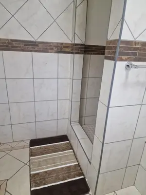 a shower with a glass door and a stair in a bathroom at Pinto City Motel in Kempton Park