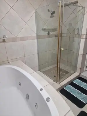 a bathroom with a tub and a glass shower at Pinto City Motel in Kempton Park