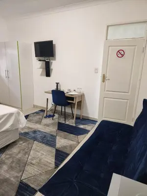 a room with a bed and a desk and a door at Pinto City Motel in Kempton Park