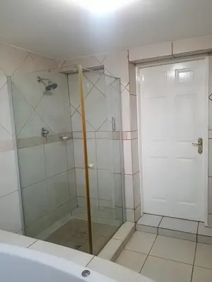 a shower with a glass door in a bathroom at Pinto City Motel in Kempton Park