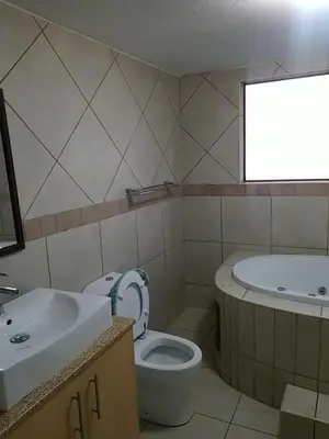 a bathroom with a toilet and a sink and a tub at Pinto City Motel in Kempton Park