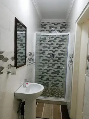 a white bathroom with a shower and a sink at Pinto City Motel in Kempton Park