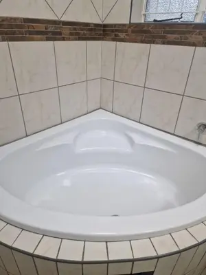 a white bath tub in a bathroom with tiles at Pinto City Motel in Kempton Park