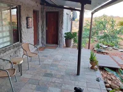 a patio with a table and chairs and a wooden door at Phomola Manor Holiday Home in Phalaborwa