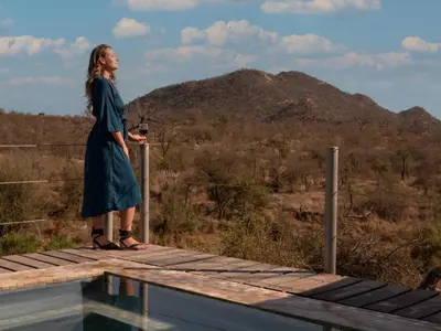 a woman standing on the edge of a deck overlooking a mountain at Phomola Manor Holiday Home in Phalaborwa
