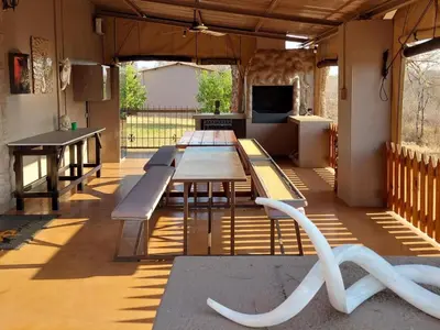 a patio with a table and benches in a room at Phomola Manor Holiday Home in Phalaborwa