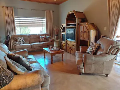 a living room with leather couches and a tv at Phomola Manor Holiday Home in Phalaborwa