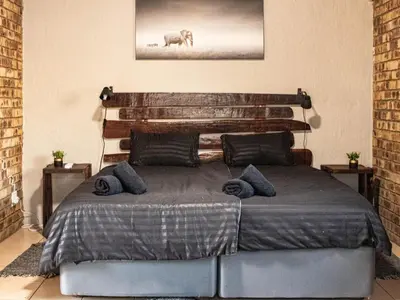 a bedroom with a large bed with a wooden headboard at Cottage@Injabulo in Marloth Park