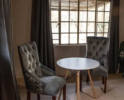 two chairs and a table in front of a window at Cottage@Injabulo in Marloth Park