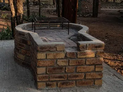 a brick fire pit with a picnic table on top at Cottage@Injabulo in Marloth Park