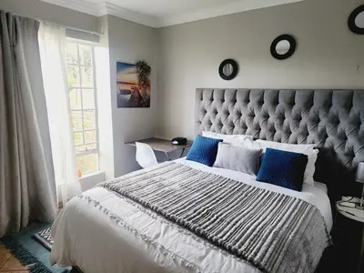 a bedroom with a large bed with blue pillows at Red Peppers in Pretoria